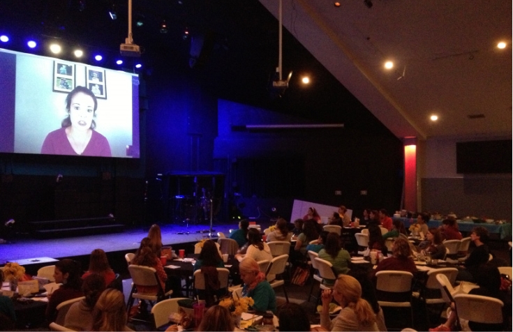 Steph on screen at a conference